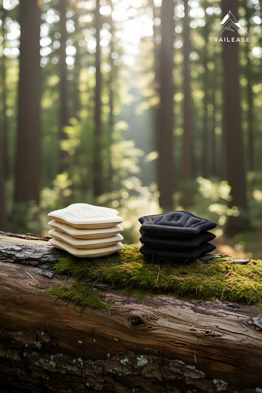 Stacks of white and black hiking achilles protector on a log in a forest with 'TrailEase' branding.